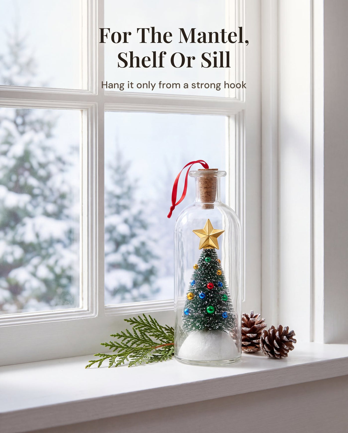 The bottle standing on a white windowsill with a cedar sprig and two pinecones, snowy evergreens outside.