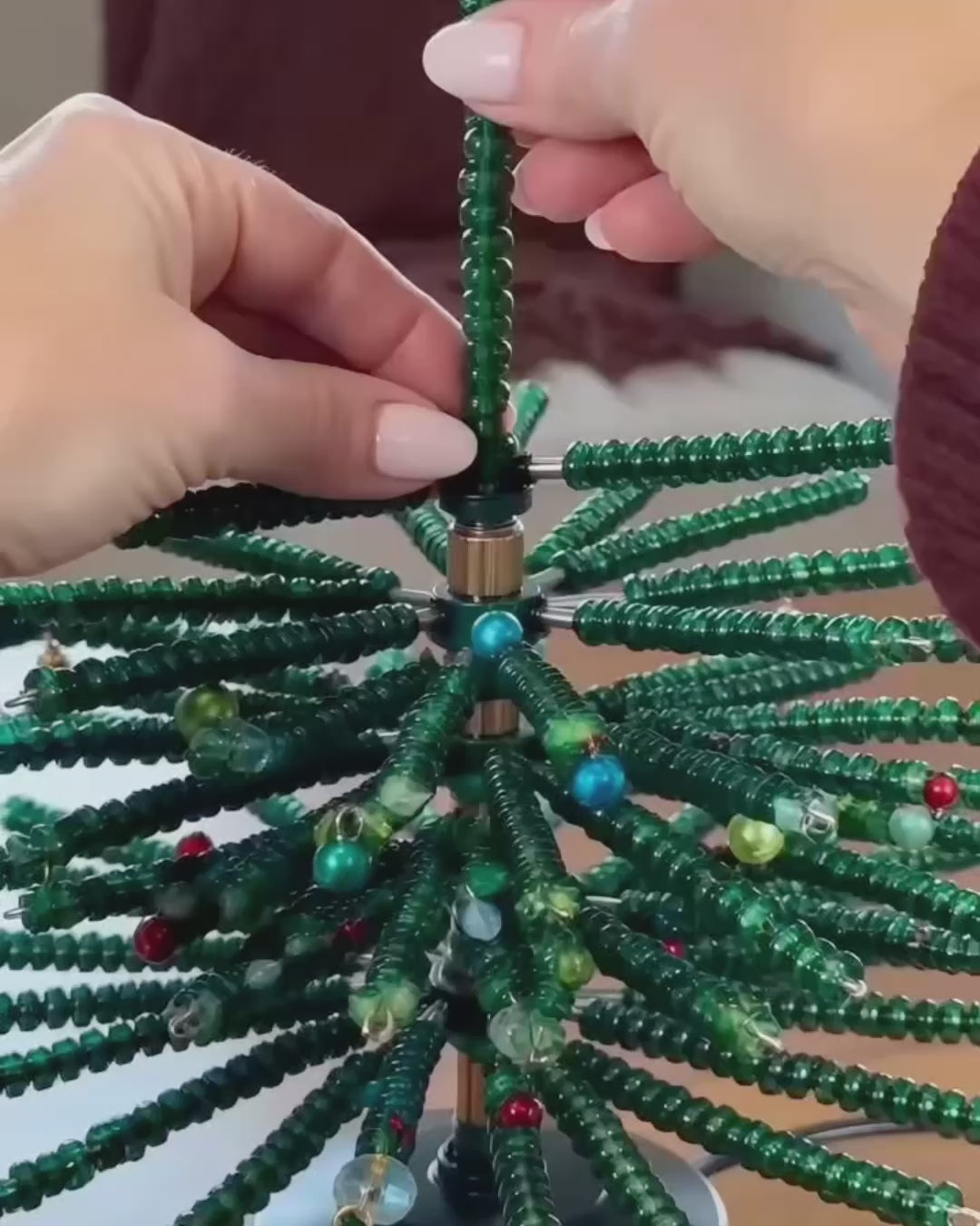 Hands building the beaded heirloom tree, then the finished tree lit up on a dining table